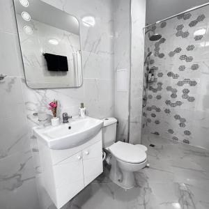 uma casa de banho branca com um lavatório e um WC em Нощувки Хранова em Plovdiv