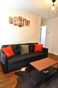 Sofá negro en la sala de estar con almohadas de color naranja en Cozy condo minutes from downtown ATL, en Atlanta