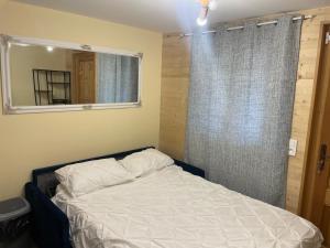 1 dormitorio con cama con espejo y ventana en Chalet Lou Via location en Abondance