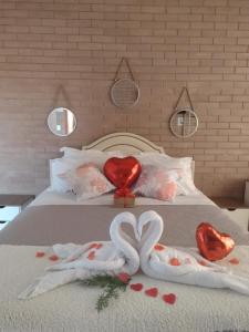 uma cama com dois corações e duas toalhas em Chalé Estância da Pinha seu Refúgio na Montanha em Santo Antônio do Pinhal