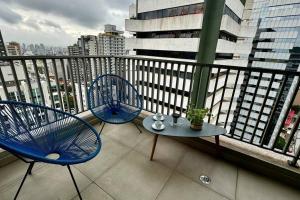 Duas cadeiras azuis e uma mesa na varanda em Studio Charmoso na Vergueiro em São Paulo