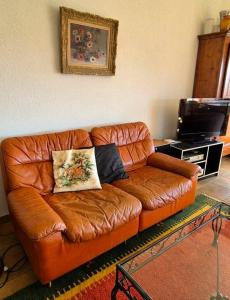 un sofá de cuero marrón en una sala de estar con TV en le Champ ensoleillé de Bogis-Bossey, en Bogis-Bossey