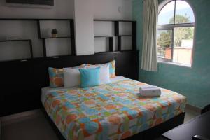 1 dormitorio con 1 cama con edredón naranja y azul en HOTEL MILLA SUITES MERIDA, en Mérida