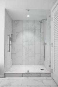 uma casa de banho com um chuveiro com azulejos brancos em JW Marriott Nashville em Nashville