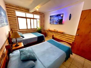 a bedroom with two beds and a tv on the wall at Capitan Brau's in Los Órganos