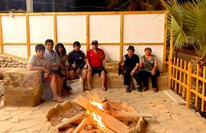 een groep mensen die rond een vuur zitten bij Capitan Brau's in Los Órganos
