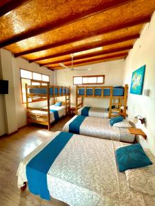 een slaapkamer met 3 bedden en een houten plafond bij Capitan Brau's in Los Órganos
