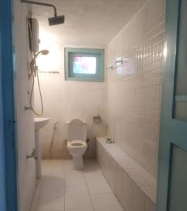 a bathroom with a toilet and a sink and a window at Piyo Vida Guesthouse in Ahangama