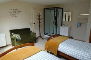 a bedroom with two beds and a green chair at Bij Suus onder de wol in Borgloon