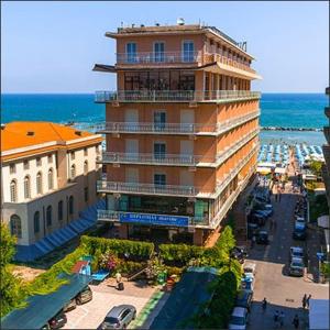 a large building next to the ocean with cars parked outside at Diplomat Marine in Cattolica