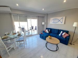 a living room with a blue couch and a table at Apartamento de Pescado Azul Gandia playa con piscina ascensor y vistas al mar in Playa de Gandia