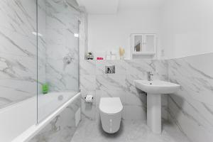 a white bathroom with a sink and a toilet and a tub at 3 Bedroom Sleep12 in London MR2 in London