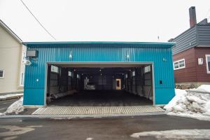 a blue building with a car garage with snow at Otaro Village - Vacation STAY 63281v in Otaru