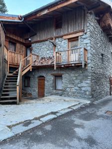 a stone house with a wooden staircase on it at Le Bouffadou in Peisey-Nancroix
