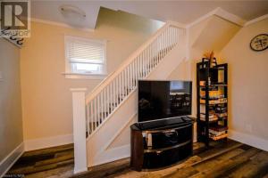 a living room with a staircase with a tv at Cozy 3 Bedroom Downtown Hideaway Cottage with Complimentary Breakfast in Niagara Falls
