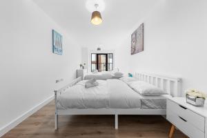 a white bedroom with a white bed and a mirror at 3 Bedroom Sleep12 in London MR2 in London