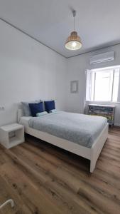 a white bedroom with a large bed with blue pillows at Happen!ng in Faro