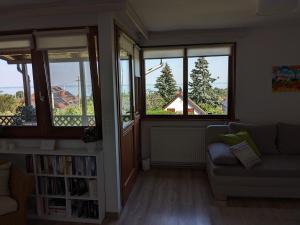 uma sala de estar com um sofá e três janelas em Gabi háza em Balatonalmádi