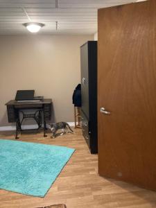 a dog walking in a room with a desk and a door at Executive Guest Suite in Edmundston