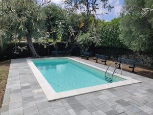 una piscina en un patio con 2 bancos en Il Poggio 3A monolocale, en San Bartolomeo al Mare