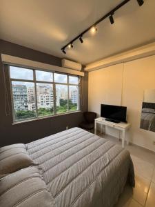 een slaapkamer met een bed en een bureau met een computer bij Studio Sezerdelo in Rio de Janeiro