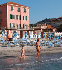 a man and a child walking on the beach at Hotel La Milanese in Pietra Ligure