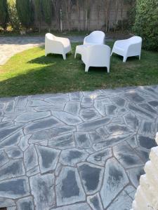 a group of white chairs sitting on a stone patio at Aire ju in Bahía Blanca