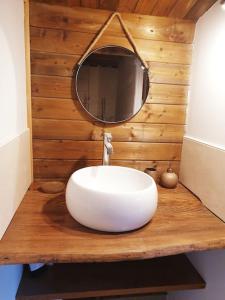 La salle de bains est pourvue d'un lavabo blanc et d'un miroir. dans l'établissement Nuit d'Amour - Chalet cocooningchauffé/climatisé, à Carsac-Aillac