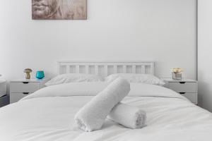 een slaapkamer met een wit bed en handdoeken bij Spacious Sleep 14 1 min from Tooting Station MR3 in Londen