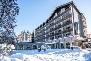 un bâtiment dans la neige avec des terrains recouverts de neige dans l'établissement Studio im Hotel Des Alpes, à Flims
