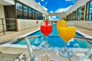 tres cócteles sentados en una mesa junto a una piscina en Flat 315 - Comfort Hotel Taguatinga, en Brasilia