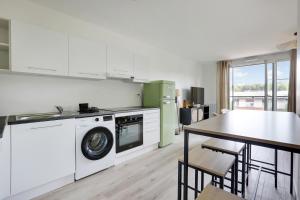 een keuken met een wasmachine en een tafel bij La Résidence Alpha Viroflay 201 - 1 chambre - 4 pers in Viroflay
