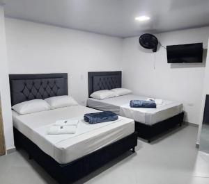 Habitación blanca con 2 camas y TV. en Apartahotel Calasanz Home, en Medellín