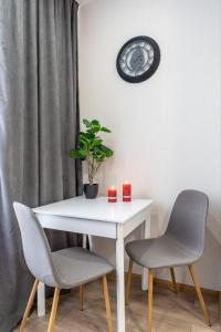 een witte tafel met twee stoelen en een klok aan de muur bij Шикарные апартаменты, Ревудского 40В, 3 мин пешком м Харьковская in Kiev