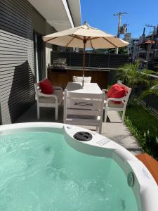 una piscina con sombrilla, mesa y sillas en Loft garden 103 Jurerê próximo praia, en Florianópolis