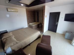 een slaapkamer met een bed, een stoel en een televisie bij HOTEL DULCES SUEÑOS in Buenaventura