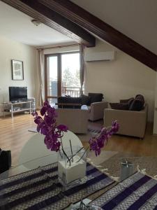 a living room with a vase with purple flowers on a table at Cozy Mountain Apartment in Borovets
