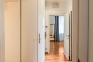 ミラノにある"Suite Elegance Brera"の白いドアとウッドフロアのオープン廊下