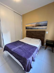 a bedroom with a bed with a purple blanket on it at LK GRAJAÚ 1 in Belo Horizonte