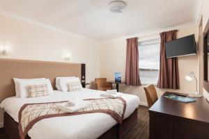 a hotel room with a bed and a desk and a window at Dunollie Hotel ‘A Bespoke Hotel’ in Broadford