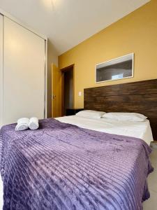 a bedroom with a purple bed with two towels on it at LK GRAJAÚ 1 in Belo Horizonte