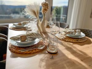 a table with plates and glasses on a wooden table at Feldbergblick mit Schwimmbad und Sauna in Lenzkirch
