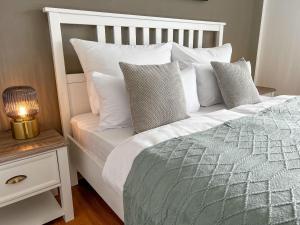 a bed with white pillows and a lamp on a night stand at Feldbergblick mit Schwimmbad und Sauna in Lenzkirch +18 photos