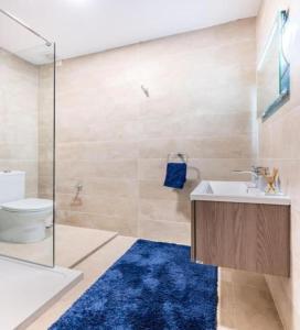 a bathroom with a sink and a toilet and a blue rug at Sea View Luxury Apartment Brand New in Valletta in Valletta