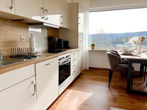 a kitchen with white cabinets and a table and a window at Feldbergblick mit Schwimmbad und Sauna in Lenzkirch