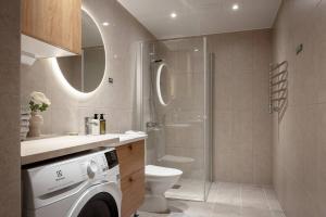 y baño con ducha, aseo y lavadora. en Modern elegance i Hagastaden en Estocolmo