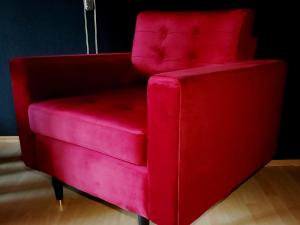 a red chair sitting on top of a wooden floor at THE BLACKTAGON Cozy Room in Frankfurt/Main