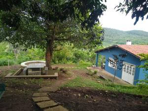 une maison bleue avec un arbre et une baignoire dans l'établissement Recanto da Felicidade, à Jacobina