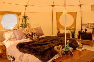 a room with a bed with a fur blanket on a table at The Follies Glamping in Maidstone