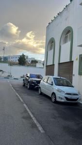 dos autos estacionados en un estacionamiento al lado de un edificio en شقة مجهزة, en Tetuán